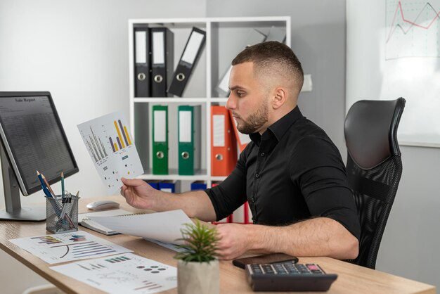 hombre-negocios-trabaja-documentos-financieros-trabaja-computadora-oficina-moderna_359031-43084
